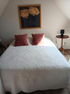 a bedroom with a white bed with a picture on the wall at L'Authentique in Mouzay