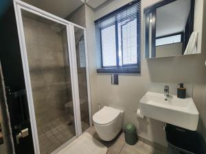 a bathroom with a toilet and a sink and a shower at GQ Short Stays at Bellamare in Summerstrand