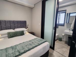 a bedroom with a large bed and a bathroom at GQ Short Stays at Bellamare in Summerstrand