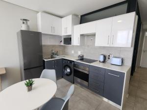 a kitchen with white cabinets and a white table at GQ Short Stays at Bellamare in Summerstrand