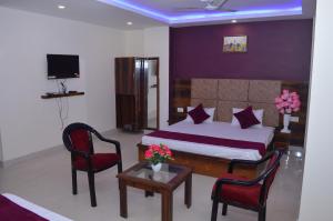 a bedroom with a bed and two chairs and a table at Hotel Exotica Haridwar in Rāiwāla