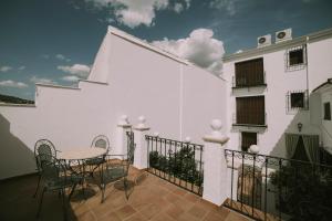 a white building with a table and chairs on a balcony at Casa Aula Minerva Sapientia 2 Habitaciones in Almedinilla