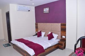 a bedroom with a bed with a purple wall at Hotel Exotica Haridwar in Rāiwāla +3 photos