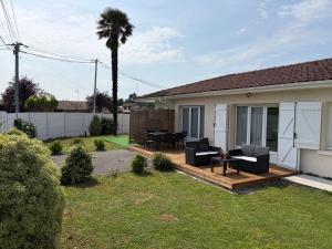 a backyard with a deck with furniture and a palm tree at Suite indépendante avec piscine proche Océan in Saint-Vincent-de-Tyrosse