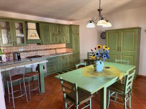 a kitchen with green cabinets and a table with a vase of flowers at Residenza Sole e Luna Capo Vaticano in Ricadi