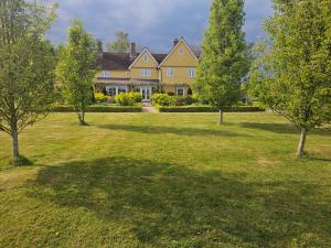 a large yellow house with trees in the yard at The Martins B&B in Chelsworth