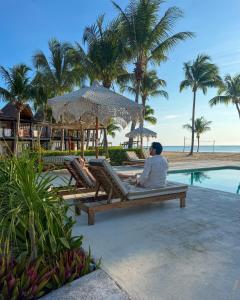 a man sitting on a bench by a pool at a resort at VR CLUB Tulum Riviera in Tulum