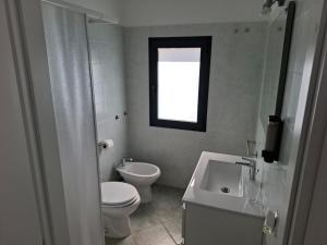 a bathroom with a toilet and a sink and a window at Su Debieddu Rooms in Solità