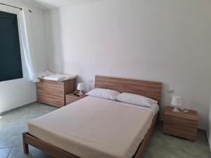 a bedroom with a bed with a wooden head board at Su Debieddu Rooms in Solità