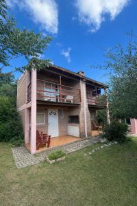 a brick house with a porch and a balcony at CABAÑAS SANTA RITA - Tanti, Córdoba in Tanti