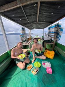 two people sitting on a boat with plates of food at Modo homestay komodo village in Komodo