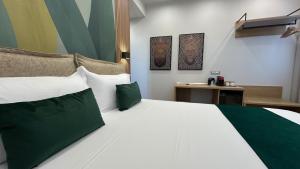a bedroom with a large bed with green and white pillows at COLIBRI Rooms in Agrigento