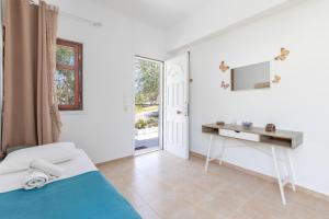 a bedroom with a bed and a desk and a window at Stella's Olive Tree House in Adelianos Kampos