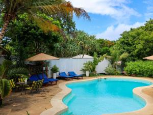 a swimming pool with chairs and umbrellas in a resort at Tradewinds Lodge in Diani Beach