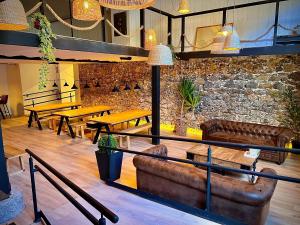 a restaurant with leather couches and tables and a stone wall at Bajamar hostel in Laredo
