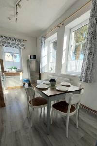 a dining room with a table and chairs and windows at Apartmány LENKA in Mikulášovice
