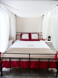 uma cama num quarto com cortinas brancas e almofadas vermelhas em La Selva Incantata em Montemiletto