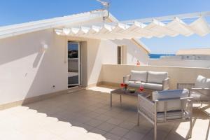 a patio with chairs and a table and an umbrella at GuestHost - Borgo 84 Marzamemi - Terrazza Mare in Marzamemi