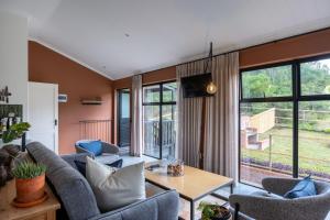 a living room with chairs and a table and windows at Cape Dutch Stay, Suite A in Sedgefield