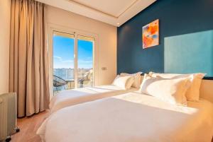 two beds in a room with a large window at Ocean Breeze 2BR Ocean View Rabat Corniche in Rabat