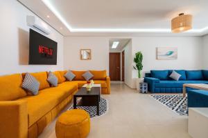 a living room with a yellow couch and blue couches at Ocean Breeze 2BR Ocean View Rabat Corniche in Rabat