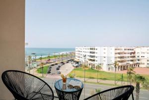 a table with two chairs and a view of the ocean at Ocean Breeze 2BR Ocean View Rabat Corniche in Rabat