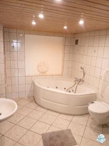 a bathroom with a tub and a toilet and a sink at Aviva ANKERPLATZ - Familien-Oase mit Gartenterrasse und 2 Schlafzimmern in Bodman-Ludwigshafen +8 photos