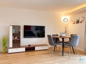 a living room with a table and a tv at Aviva ANKERPLATZ - Familien-Oase mit Gartenterrasse und 2 Schlafzimmern in Bodman-Ludwigshafen
