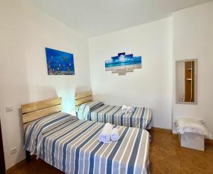 two beds in a small room with striped sheets at Francesca Appartamento con giardino in Levanto