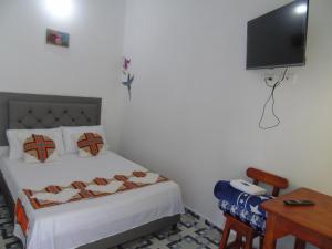 a bedroom with a bed with a tv on the wall at Vista Farallones Hostel in Jardin