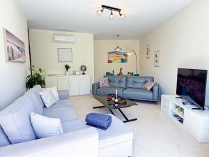 a living room with a blue couch and a tv at Tavira Escape with Pool by BeCherish in Tavira