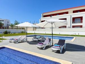 a pool with lounge chairs and umbrellas next to a building at Tavira Escape with Pool by BeCherish in Tavira