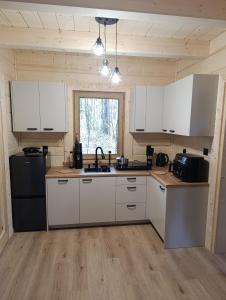 a kitchen with white cabinets and a black refrigerator at Sosnowy Oddech in Samsonów