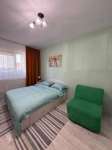 ein Schlafzimmer mit einem Bett und einem grünen Ottomanen in der Unterkunft Mary's Studio in Ipoteşti