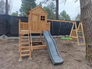 a wooden playground with a slide and a tree at Sosnowy Oddech in Samsonów