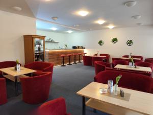 a waiting room with red chairs and tables at Hotel SOREA MÁJ in Liptovský Ján