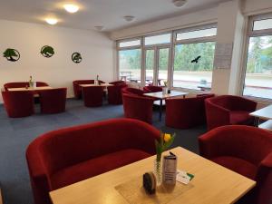 a restaurant with red chairs and tables and windows at Hotel SOREA MÁJ in Liptovský Ján