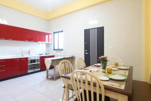 a kitchen with red cabinets and a wooden table and chairs at 橘子喵旅宿 in Hengchun South Gate