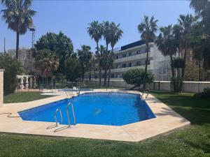 a swimming pool in a park with palm trees and a building at Spacious Apartment with 3 pools very central in Benalmádena