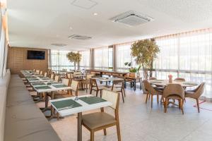 a dining room with tables and chairs and windows at Beach Class Summer resort condominium by Carpediem in Porto De Galinhas