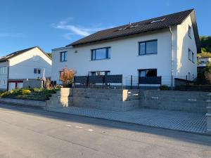 a white house with a brick retaining wall at Aviva ANKERPLATZ - Familien-Oase mit Gartenterrasse und 2 Schlafzimmern in Bodman-Ludwigshafen