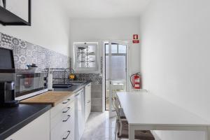 a kitchen with white cabinets and a table in it at Azuaga House Sunny Charming Apt in Vila Nova de Gaia