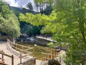 a bridge over a river with trees and a hill at Raízes da Serra - Casa Lapa in Lapa dos Dinheiros