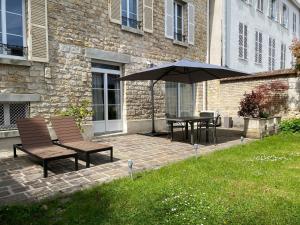 a patio with two chairs and a table with an umbrella at Le Petit Jard'Inn in Chalons en Champagne