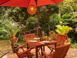 a wooden table with chairs and an umbrella at Studio Anthurium in Gros-Morne +4 photos