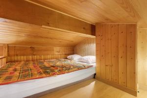 a bed in a room with a wooden wall at Petite Villa Mitoyenne Dans Pinède in Lacanau-Océan
