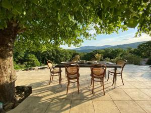 a table and chairs on a patio under a tree at Villa les Jules in Thoard
