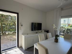a white dining room with a table and a tv at Appartamenti Federica 12T in Milano Marittima