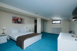 a bedroom with a white bed and blue carpet at Vila Turistică Fabian in Botoşani
