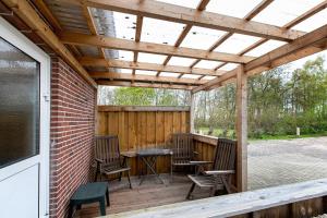 a wooden pergola with chairs and a table on a deck at Haus Sonneneck in Oesterdeichstrich